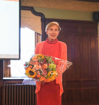 A professor poses for a photo holding flowers.