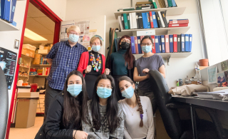 Professors and students pose for a photo in a science lab office.