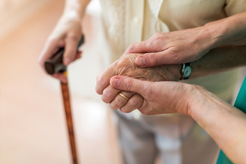 hand of elderly person supported by caregiver
