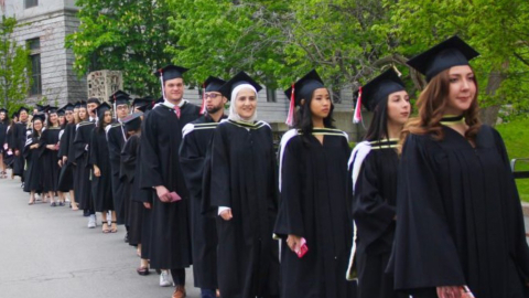 A line of students dressed up in black graduation gowns and hats