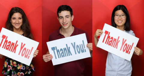 Three people holding signs saying thank you