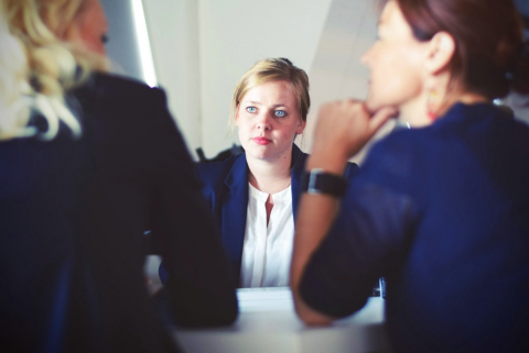 Three women in business attire, one being interviewed by the other two