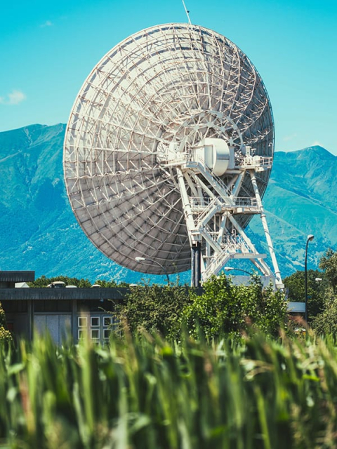 Large white satellite dish outdoors with mountains in the background