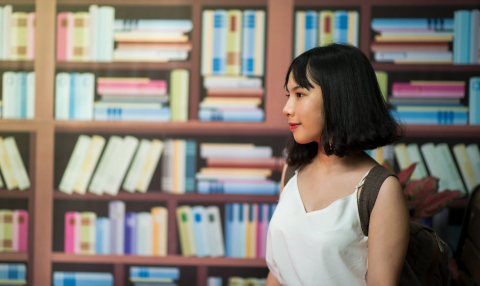 Girl standing in front of colourful books. 