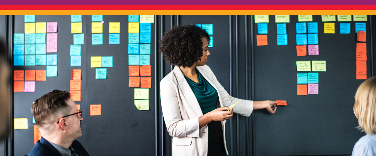 People looking at sticky notes on a wall