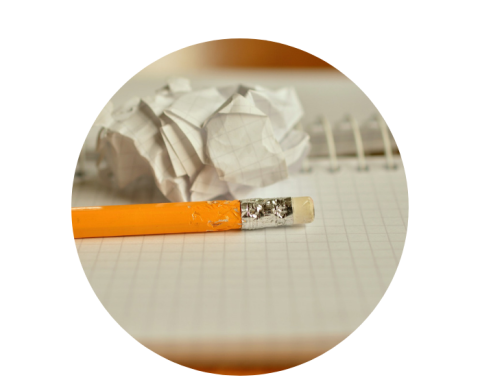 Pencil lying on top of a note book beside a crumpled piece of paper