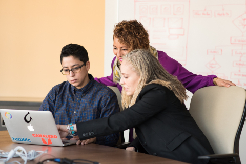 Three teachers looking at a laptop