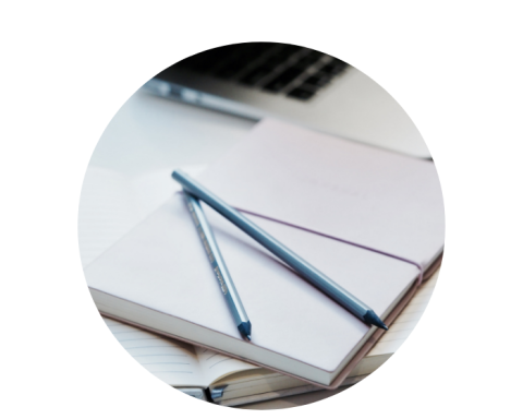 two pencils lying on top of a blank notebook