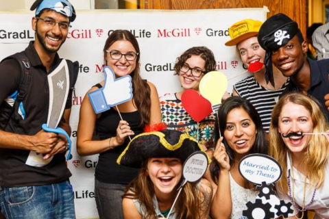 Students posing in front of a GradLife photo backdrop