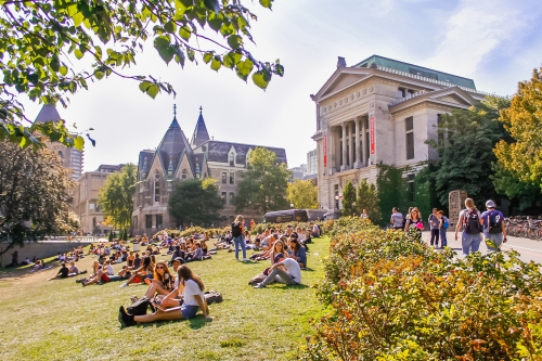 Students lounge on a grassy hill in front of Redpath Museum