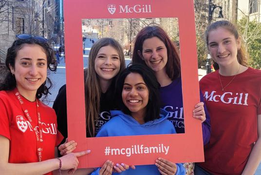 Students gathered outside within a frame that has #mcgillfamily written on it. 