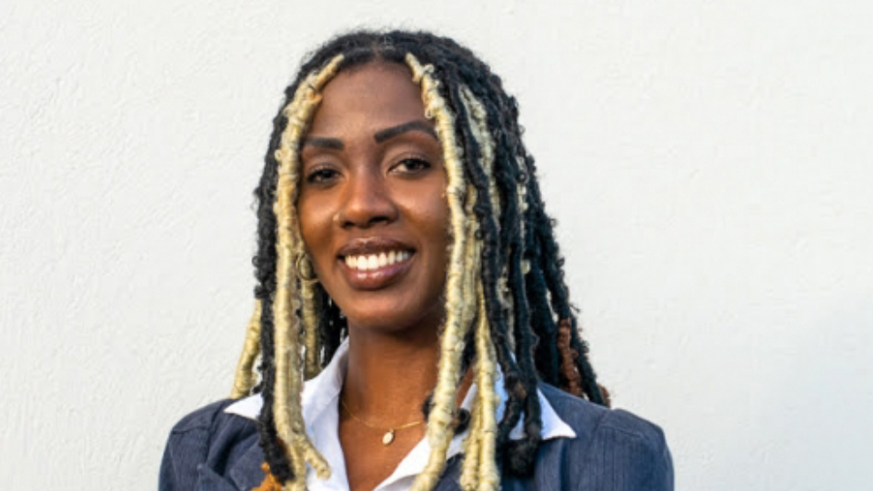 Asia Blackman - young black woman wearing locs and a suit