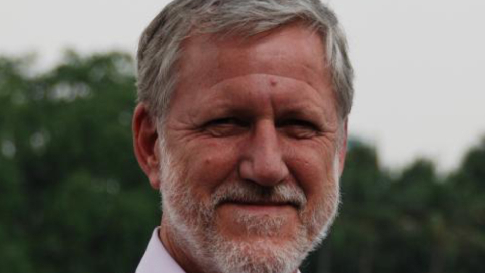 Dr. Charles Larson - middle-aged man with grey hair and beard posing outside