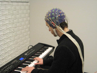 Person with EEG headcap plays a piano