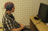 Man wearing an EEG cap is sitting in front of a computer
