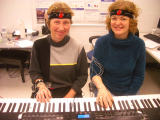 Two pianists wearing motion capture headsets and handsets