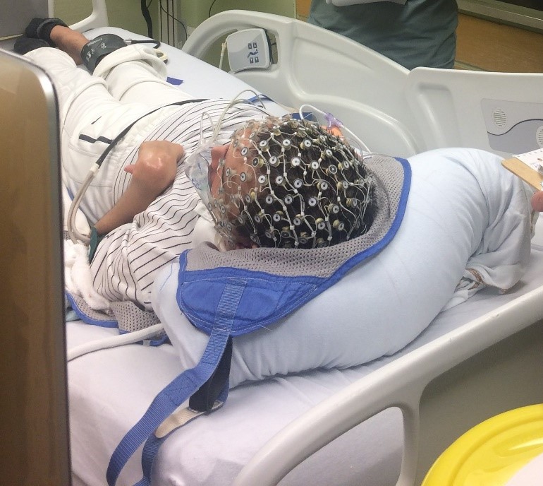 Patient lying in hospital bed with EEG cap on head