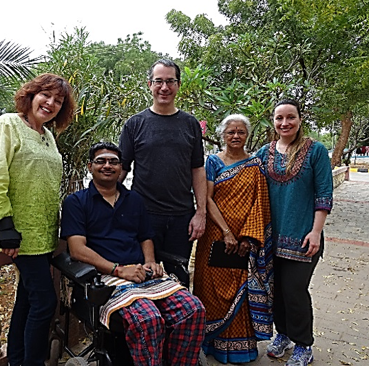 Group of five people standing on ASSA grounds, one person using a wheelchair.