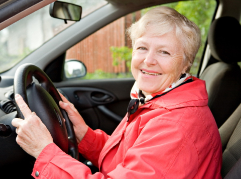 Femme âgée souriant et conduisant 