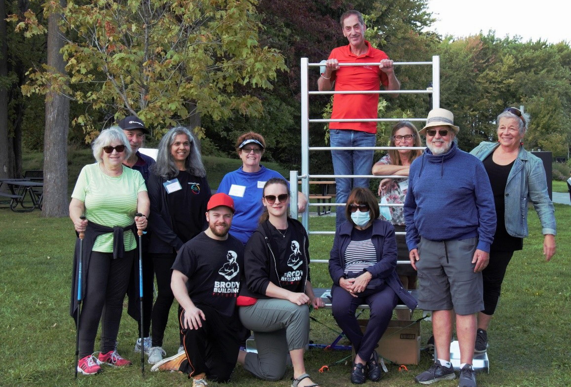 group of people sitting and standing around outdoor exercise structure