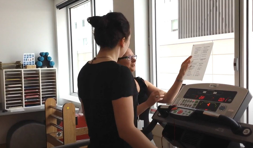 Researcher explaining information to a young participant who is on a treadmill