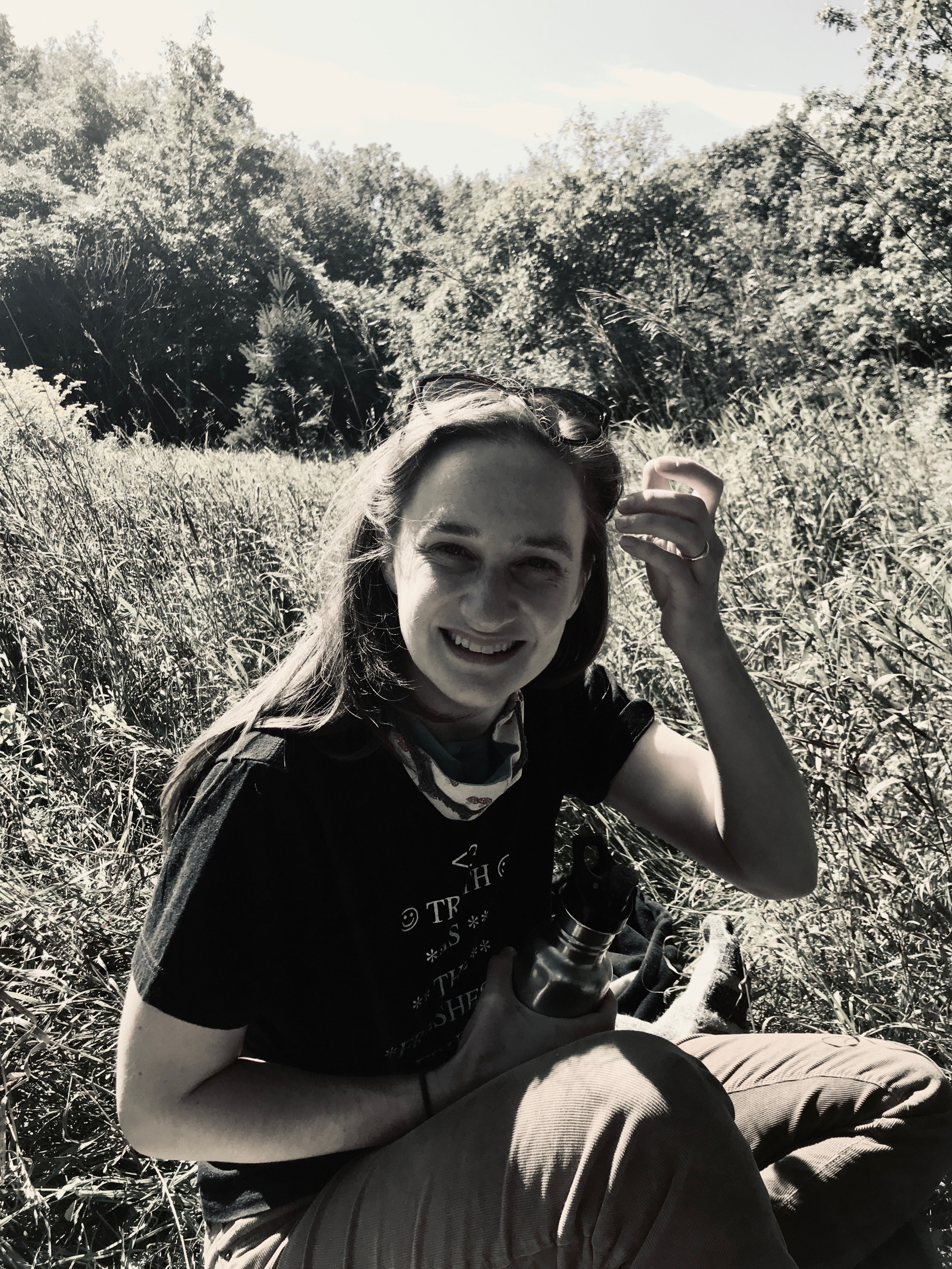 Anna sitting outside in a field of grass