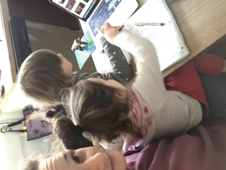 Anna sits in front of her laptop with her two children on her lap