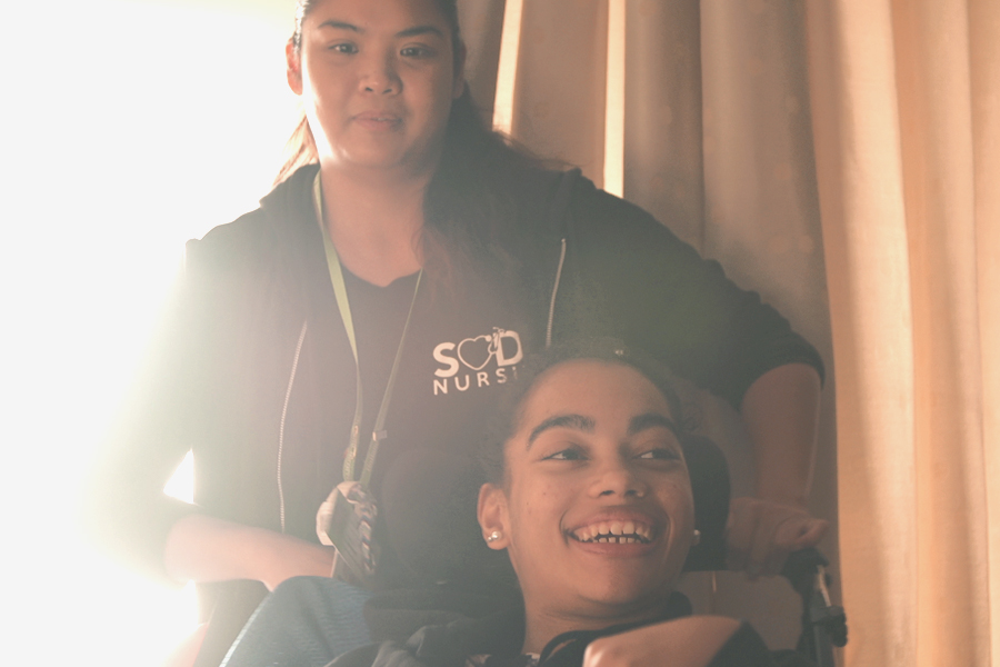 Nurse wheels a smiling young patient in a wheelchair