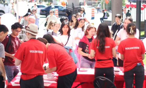 4 students in red McGill t-shirts, volunteering with Campus Life & Engagement, talk with students at an outdoor tabling event
