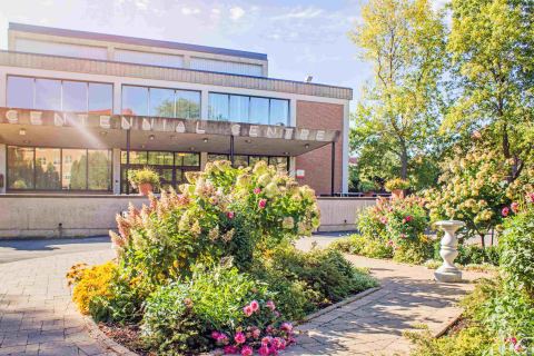 The front facade of the Cetennial Centre, viewed from the garden in full bloom.