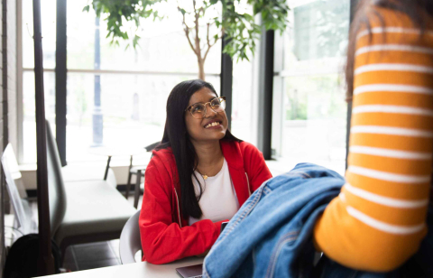 An AskMcGill student navigator seated inside the Brown Building assists a student.