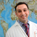 Headshot of Cedric Yansouni standing in front of a world map