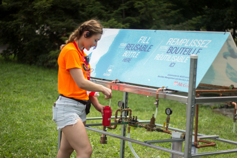 A McGill student refills their water bottle at the custom-made Refill McGill water cart at frosh. 