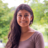 Divya, a young woman, smiles for the camera.