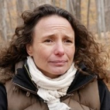 A woman stares past the camera in a forest