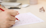 Close up of a hand filling in a scantron exam