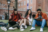 Three students sitting outside laughing while working