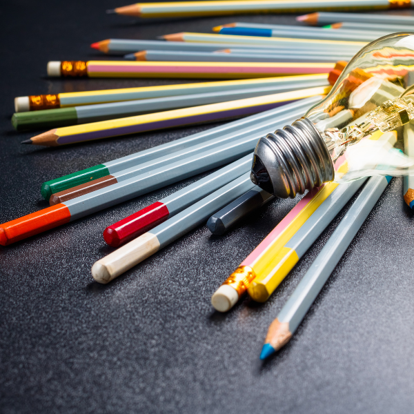 a group of coloured pencils and a lightbulb