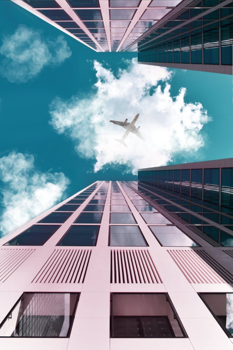 airplane flying between buildings 