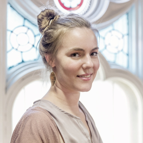 Portrait of a student in front of a stained glass window.