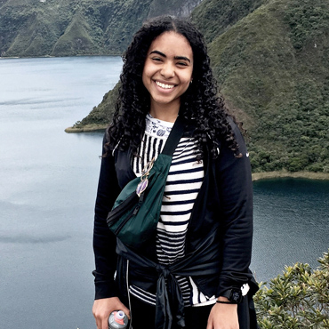 Portrait of a student standing in front of a hilly background.