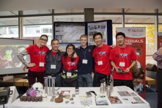 Six students standing together behind a presentation table.