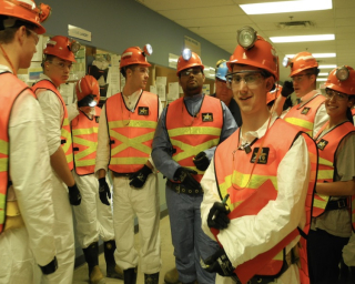 Group of students dressed in mining safety equipment.