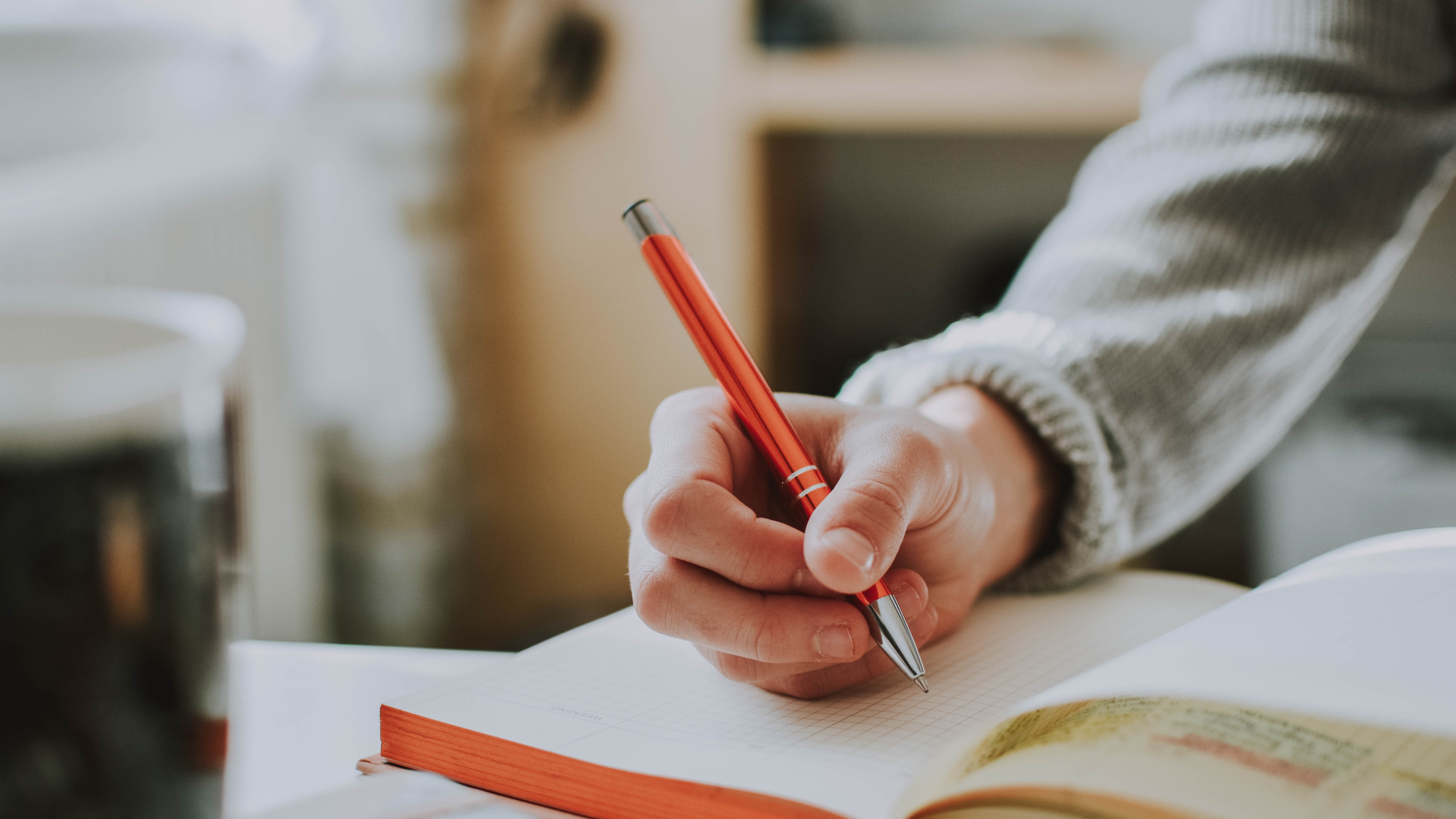 Image of hand with pen writing in a notebook