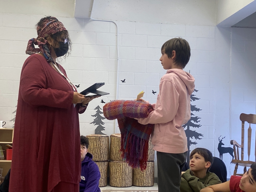 facilitator holding feathers, standing with student holding blanket