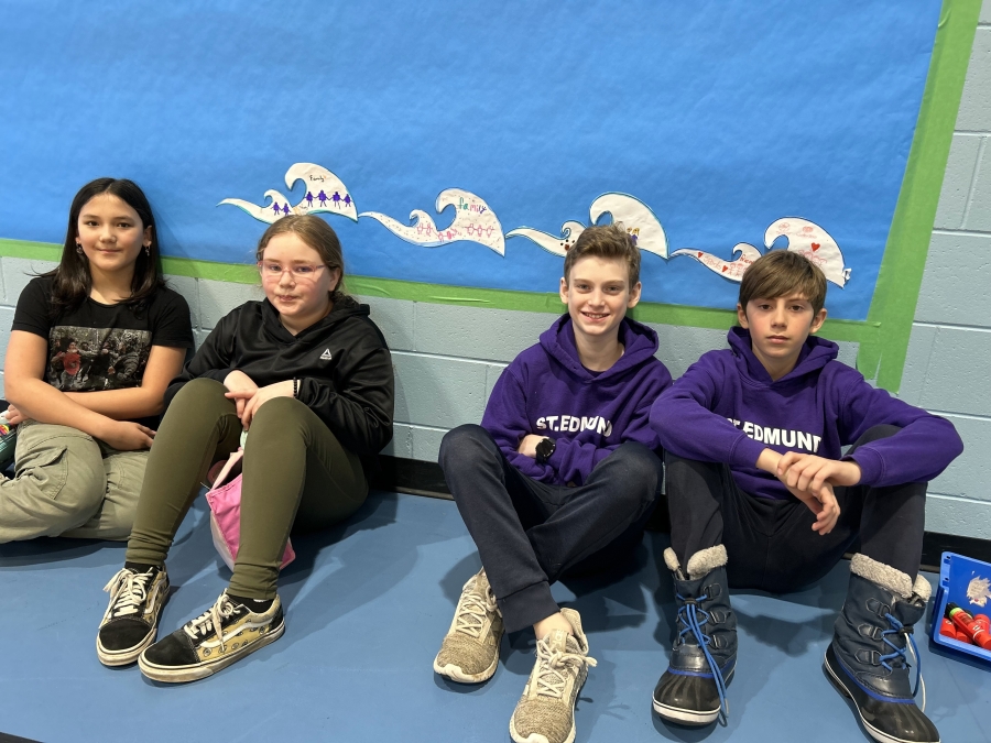 students sitting against wall with waves behind