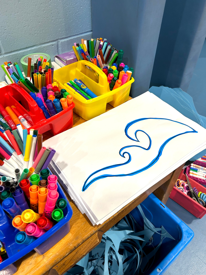 close up of wave drawing with bins of markers