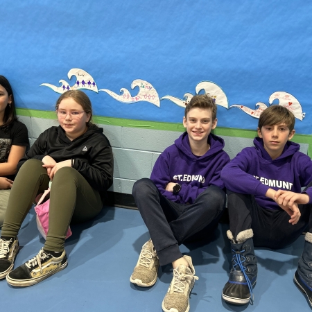 students sitting against wall with waves behind