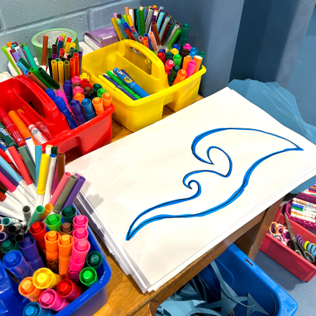 close up of wave drawing with bins of markers