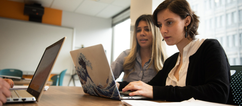 2 students sitting down together in front of a laptop